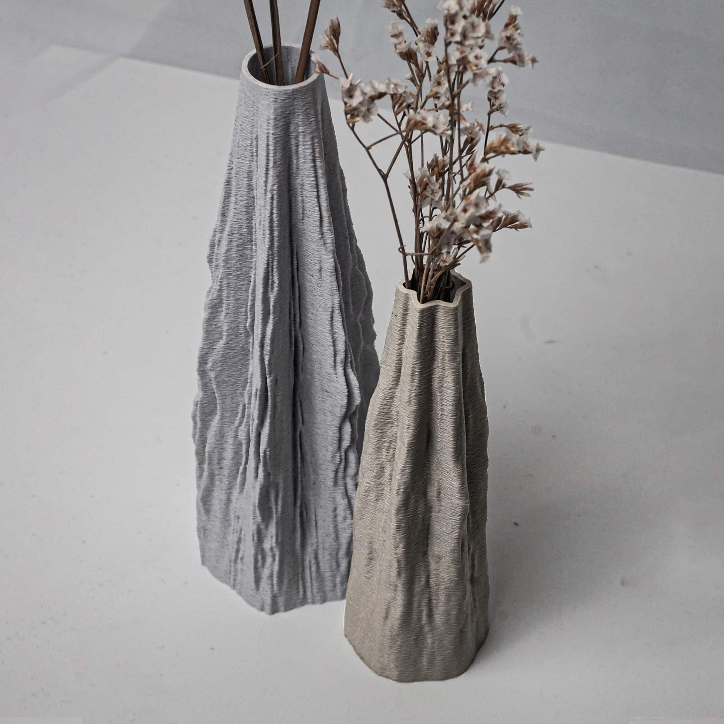 Two textured vases on a light gray surface with minimal background