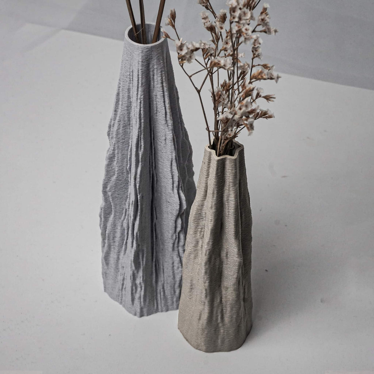 Two textured vases on a light gray surface with minimal background