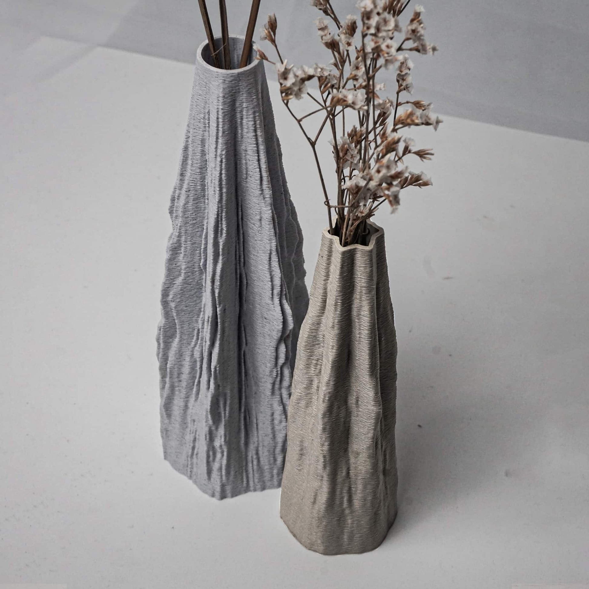 Two textured vases on a light gray surface with minimal background