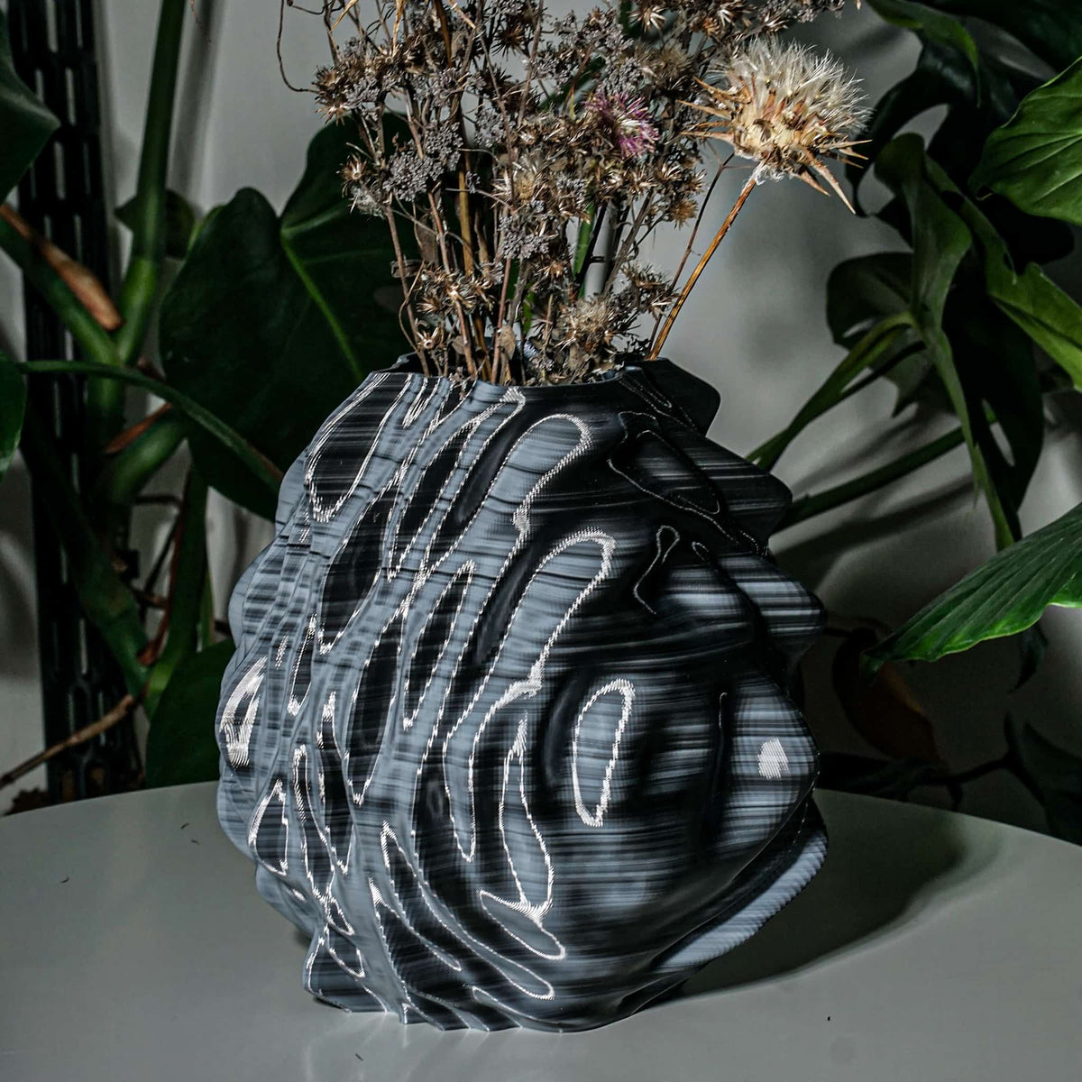 Black and white 3d print vase with dried flowers on a white surface