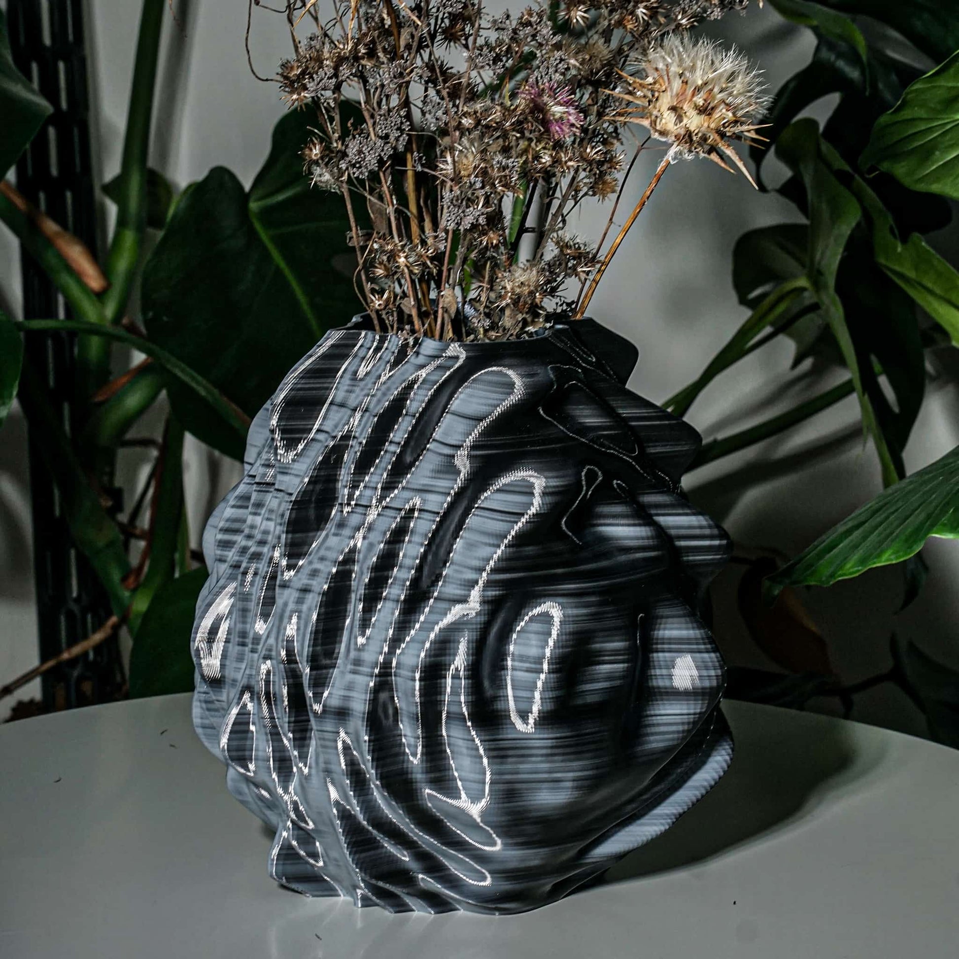 Black and white 3d print vase with dried flowers on a white surface