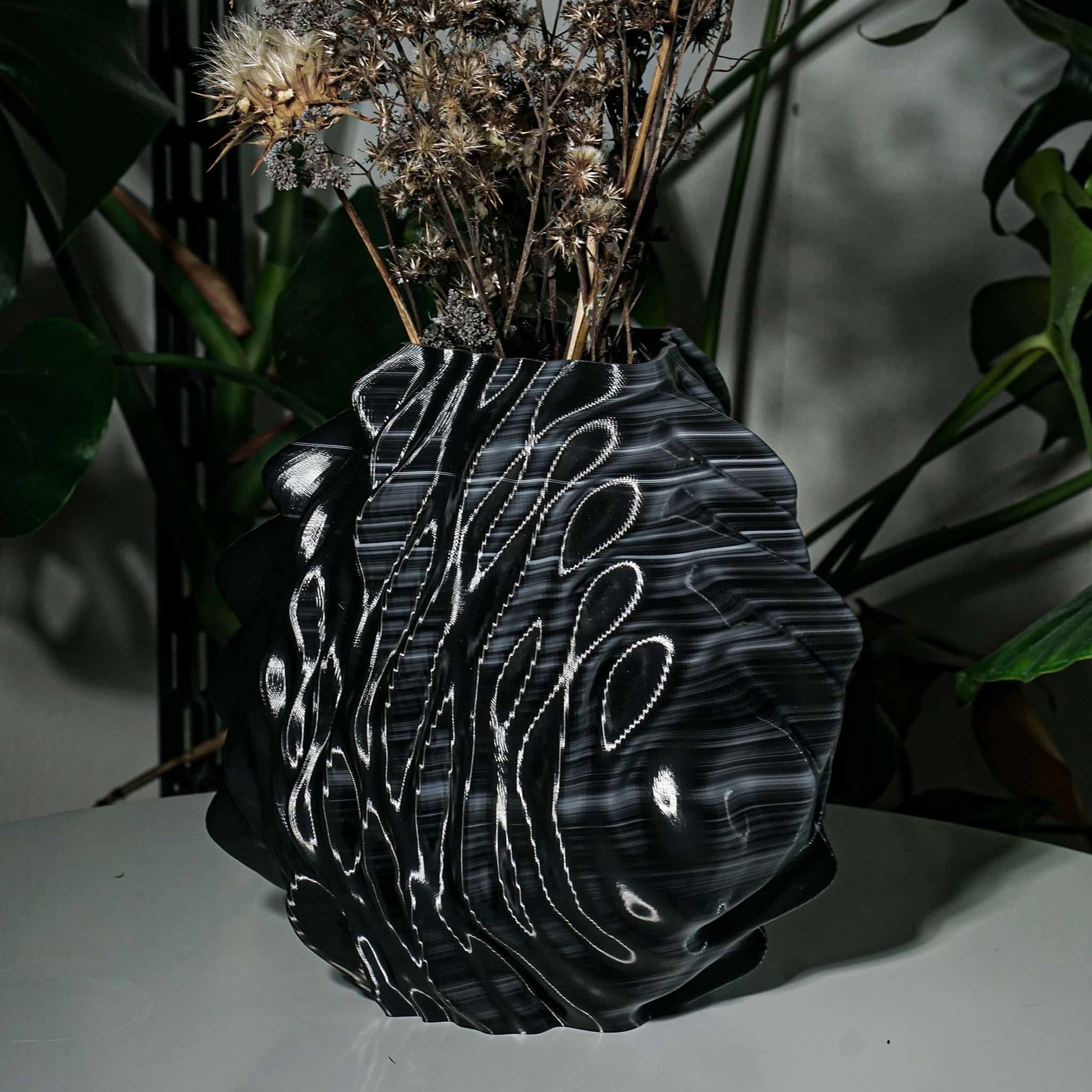Black and white patterned vase with dried flowers on a dark background