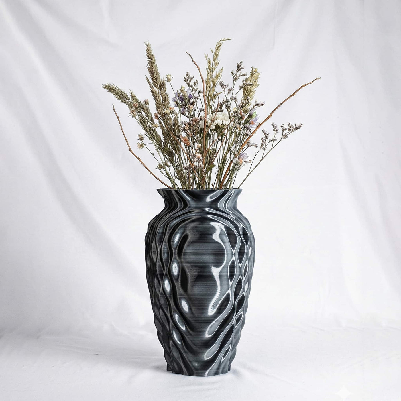 The ONDA Resonance vase holding a bunch of pale dried flowers, on a white ground