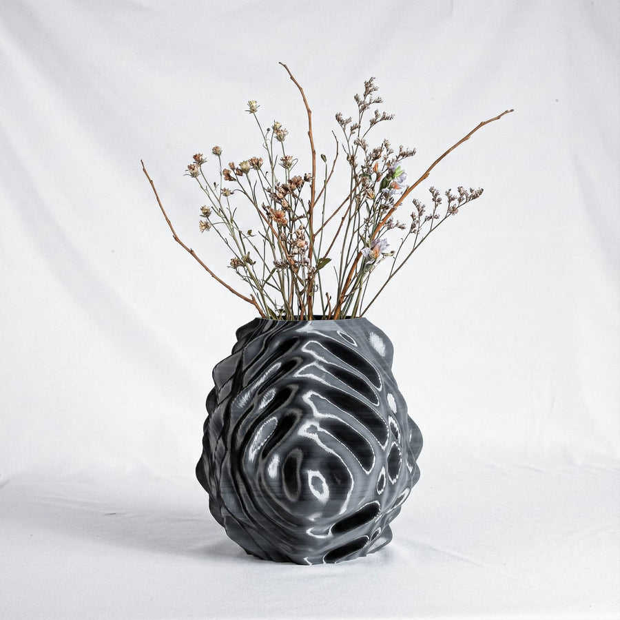 Black textured vase with dried plants on a white background