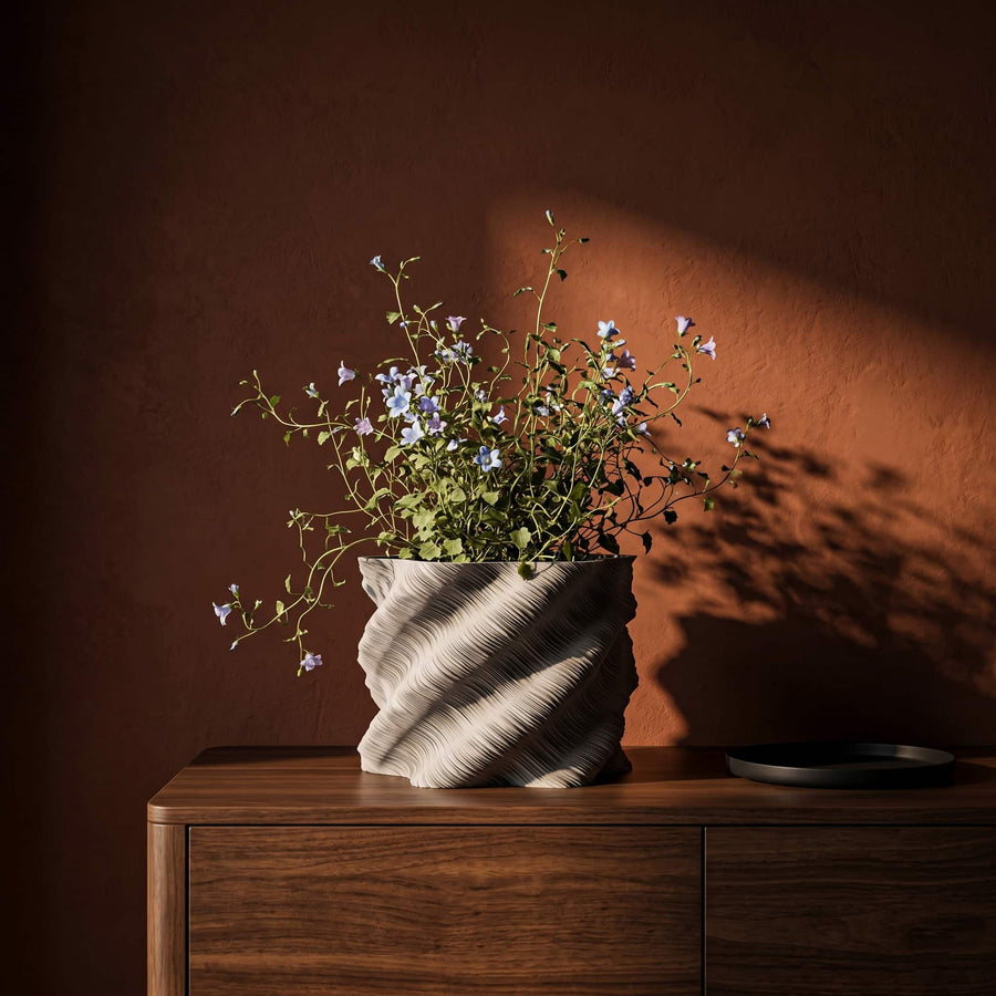 Calisia vase with flowers on a wooden surface against a red brown wall