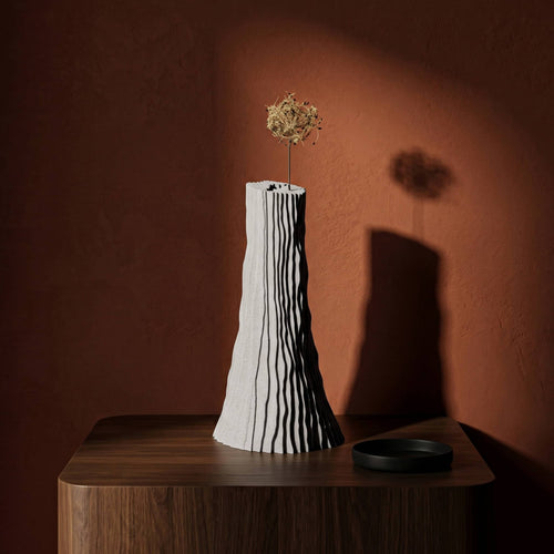 Carsia vase on a dark wood surface and brown red wall on background