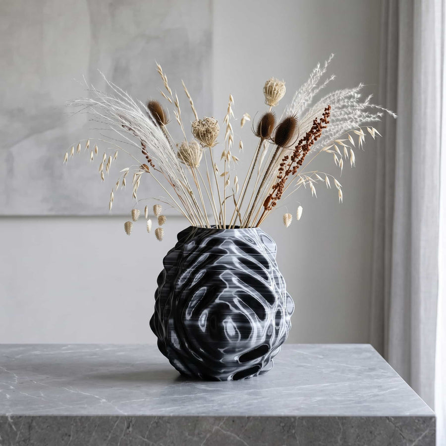 ONDA Interference 3D-printed vase in black and white, holding dried grasses and teasels on a grey marble console