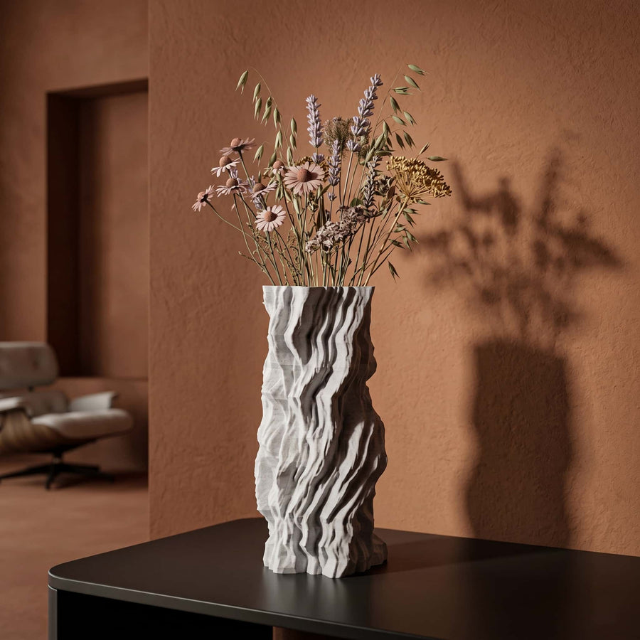 Telluria vase with rock pattern on a table against a warm-toned wall.
